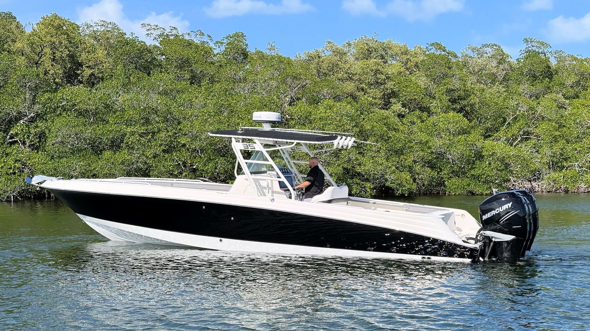 White Wellcraft center console boat cruising on calm water beside dense green mangroves
