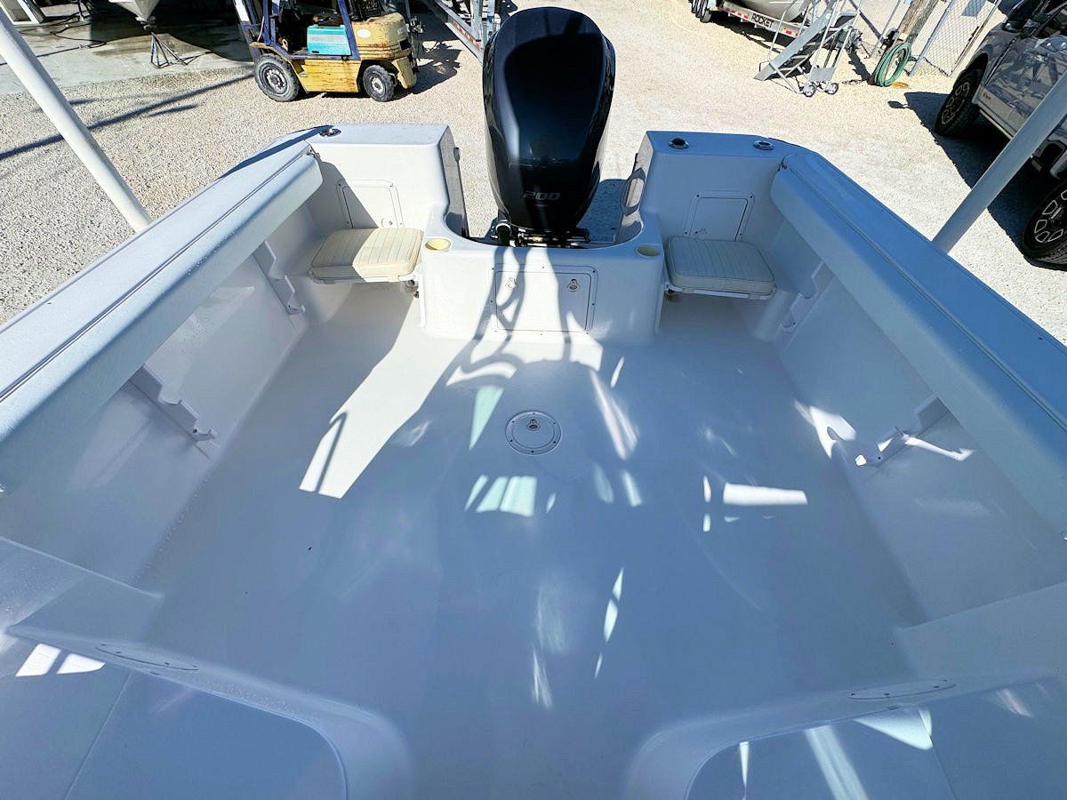Empty white fishing boat deck with a black outboard motor.