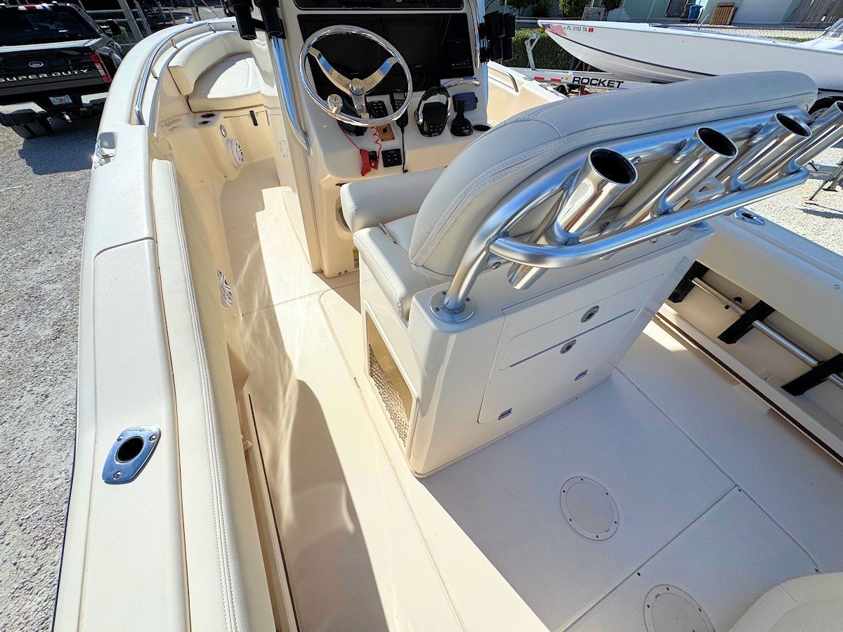 Interior of a beige and white boat with fishing rod holders, steering wheel, and seating.