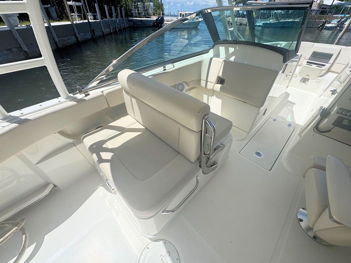 Boat interior with white seating and windshield, water in background.