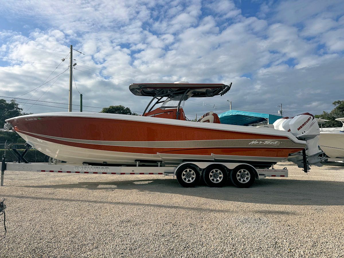 Orange and white powerboat on a trailer, under a cloudy sky.