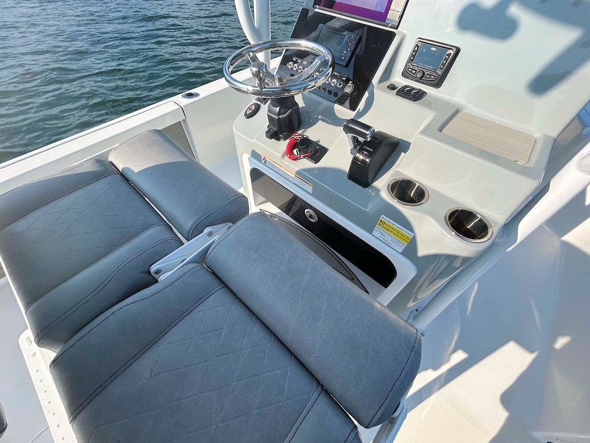 Tan boat helmstation with steering wheel, gauges, and two cushioned seats.