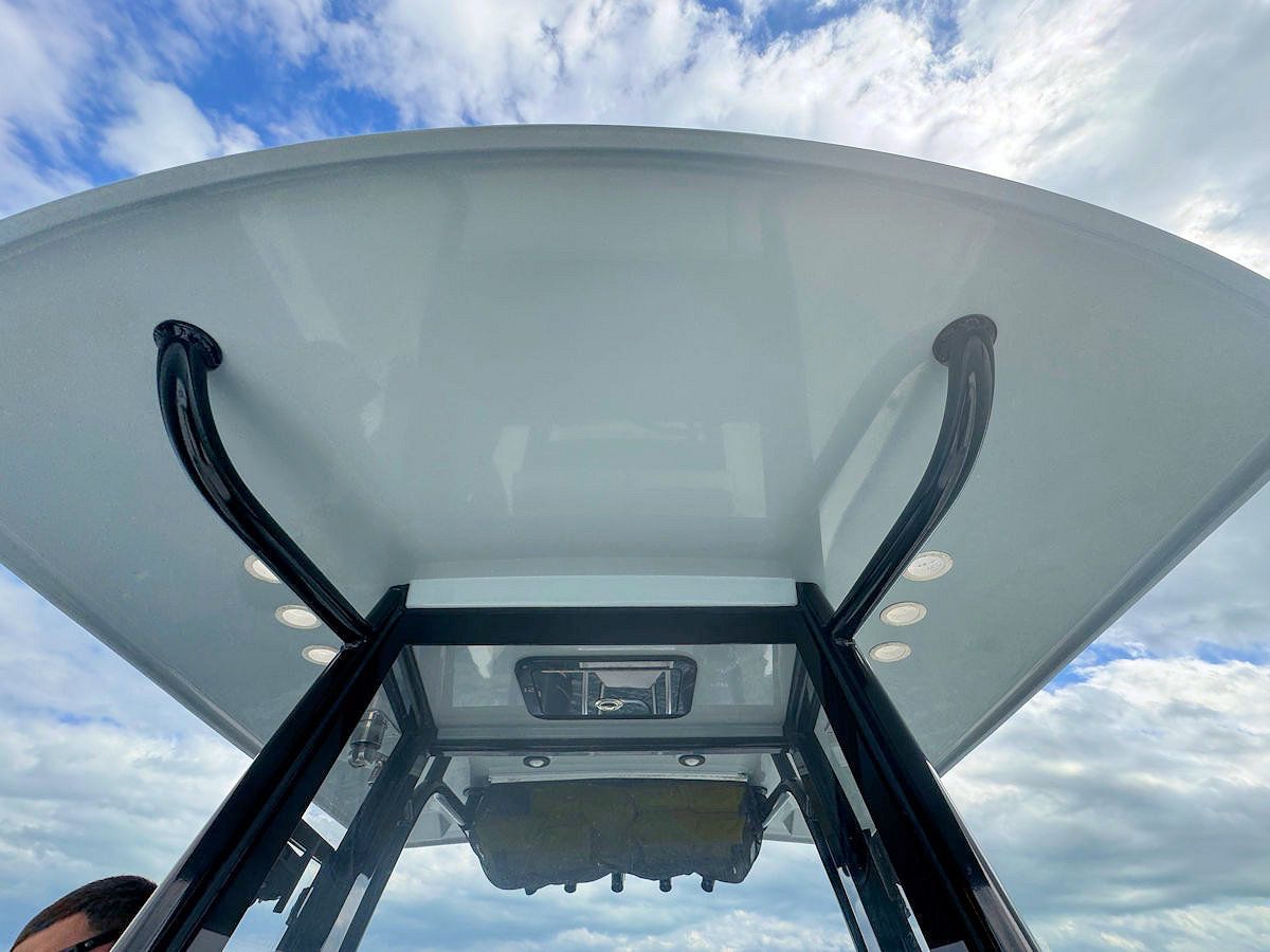 Boat T-top with curved supports, white surface, and lights, against a partly cloudy blue sky.