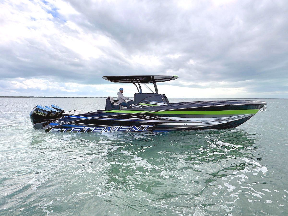 A green and black speedboat floats on water under a cloudy sky.