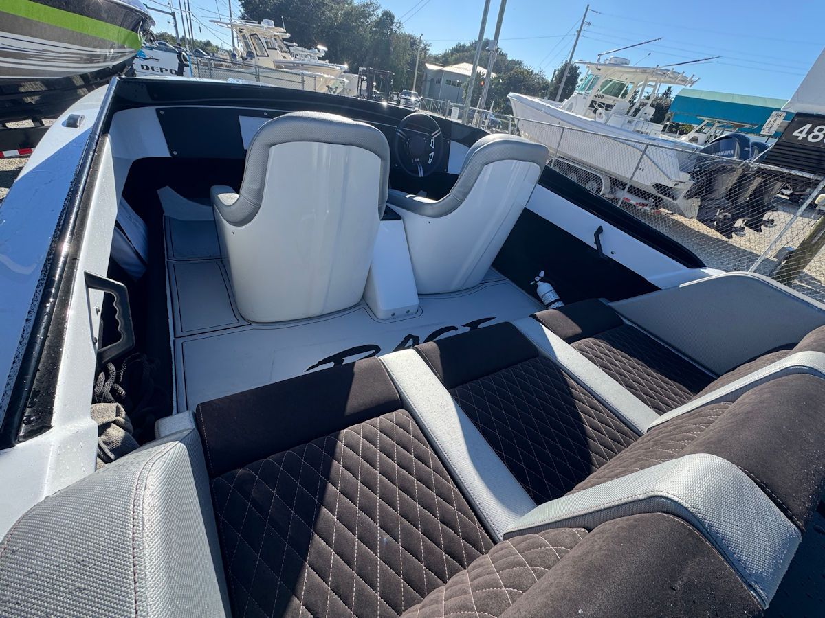 Interior view of a black and white speedboat with gray seating, dashboard and steering wheel.