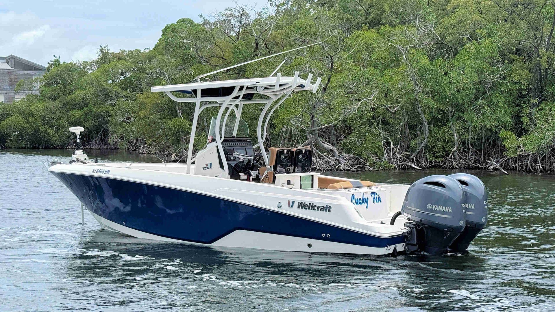 Wellcraft 242 Fisherman boat with a T-top cruising on calm water near mangrove trees