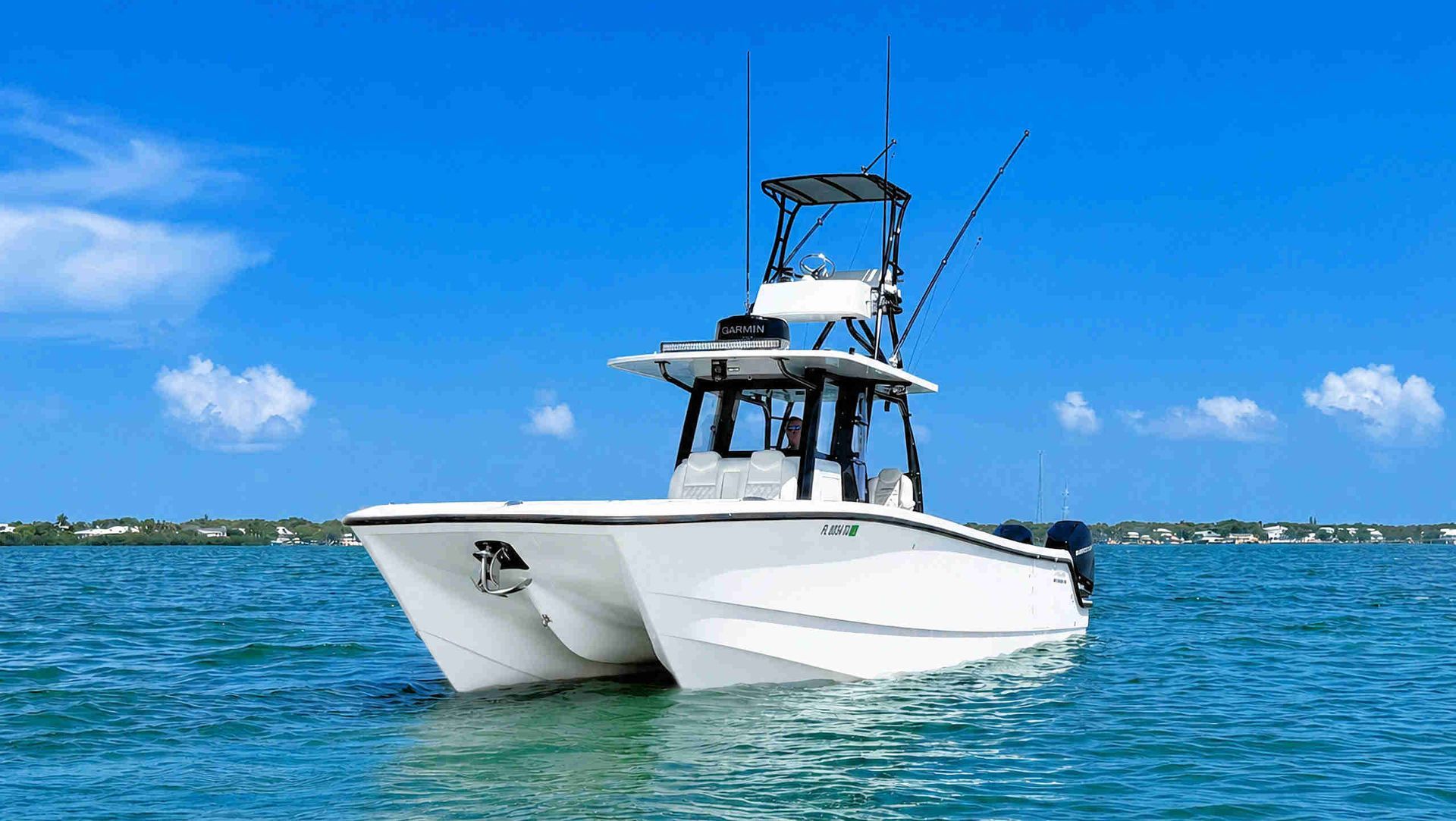 White catamaran center console fishing boat on blue water under a bright sky