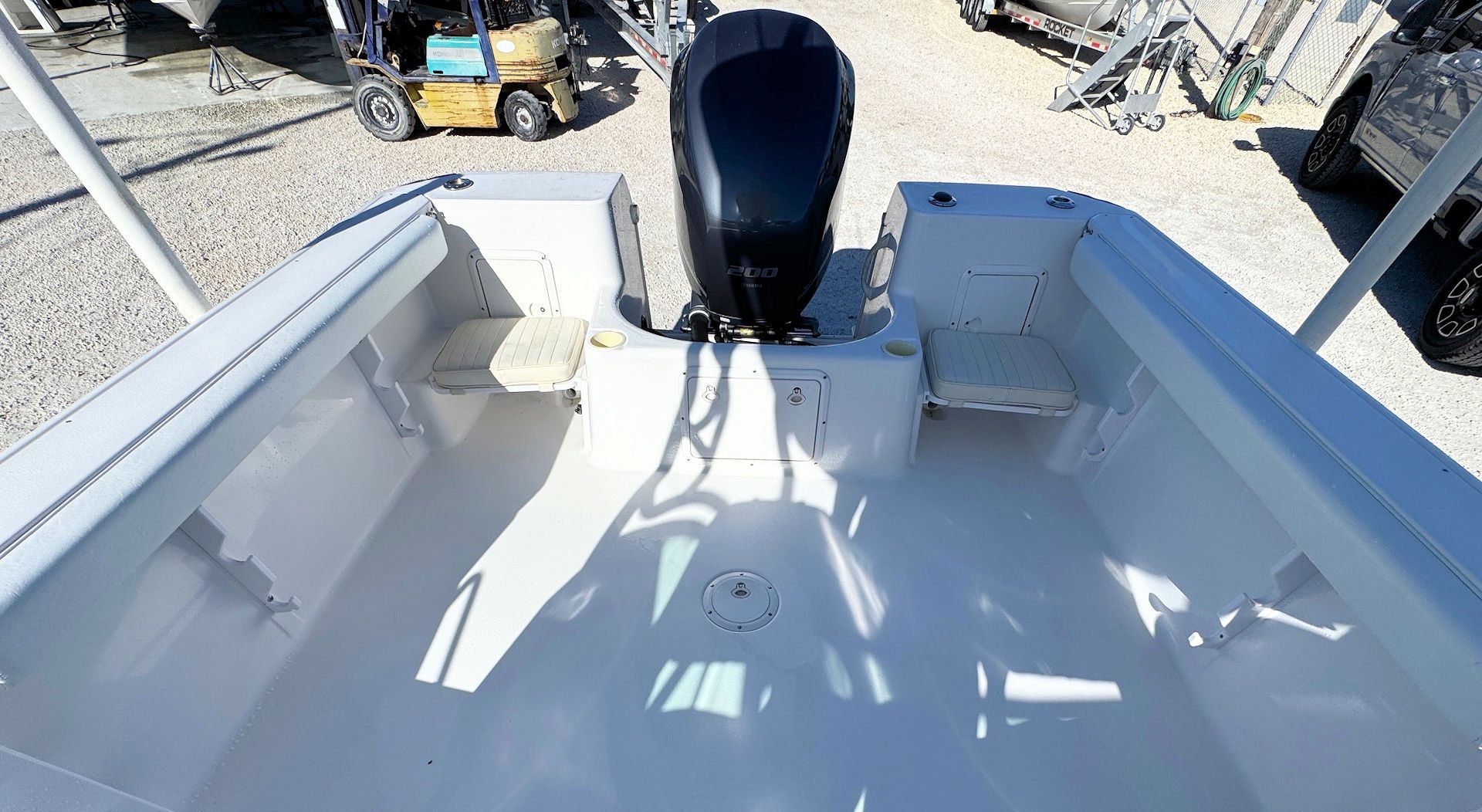 A view from the deck of a boat looking aft at a black outboard motor mounted on the white fiberglass stern.