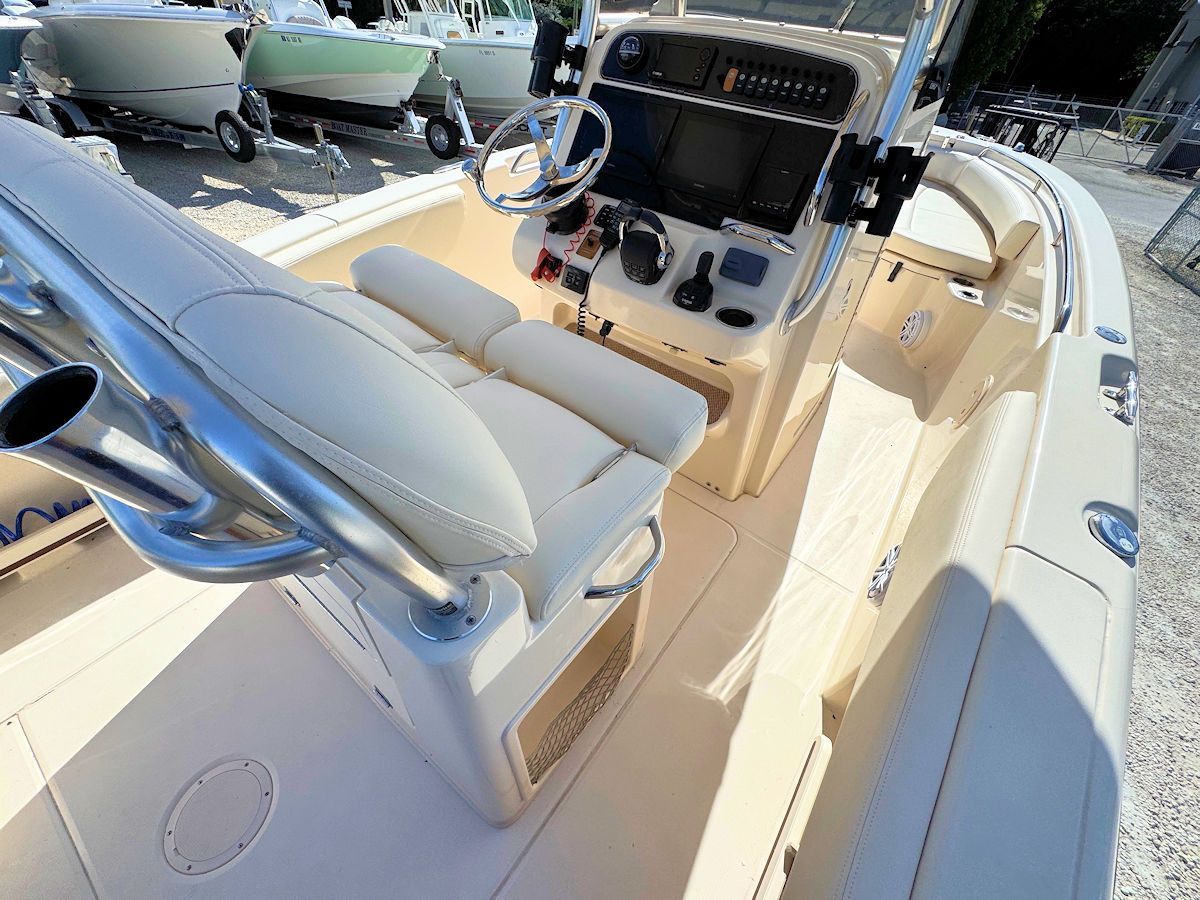 Beige boat interior with seats, steering wheel, and console.
