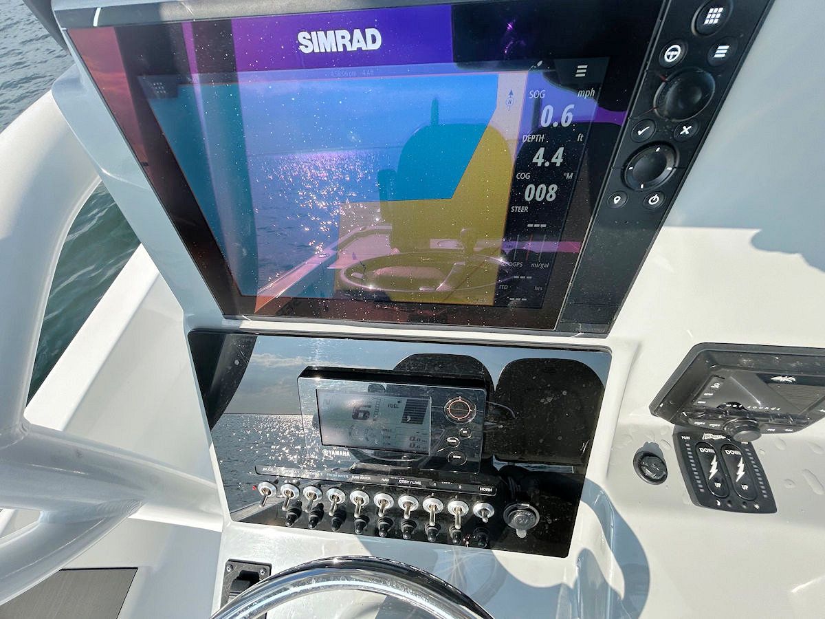 Boat dashboard with Simrad screen displaying water data, gauges, and switches.