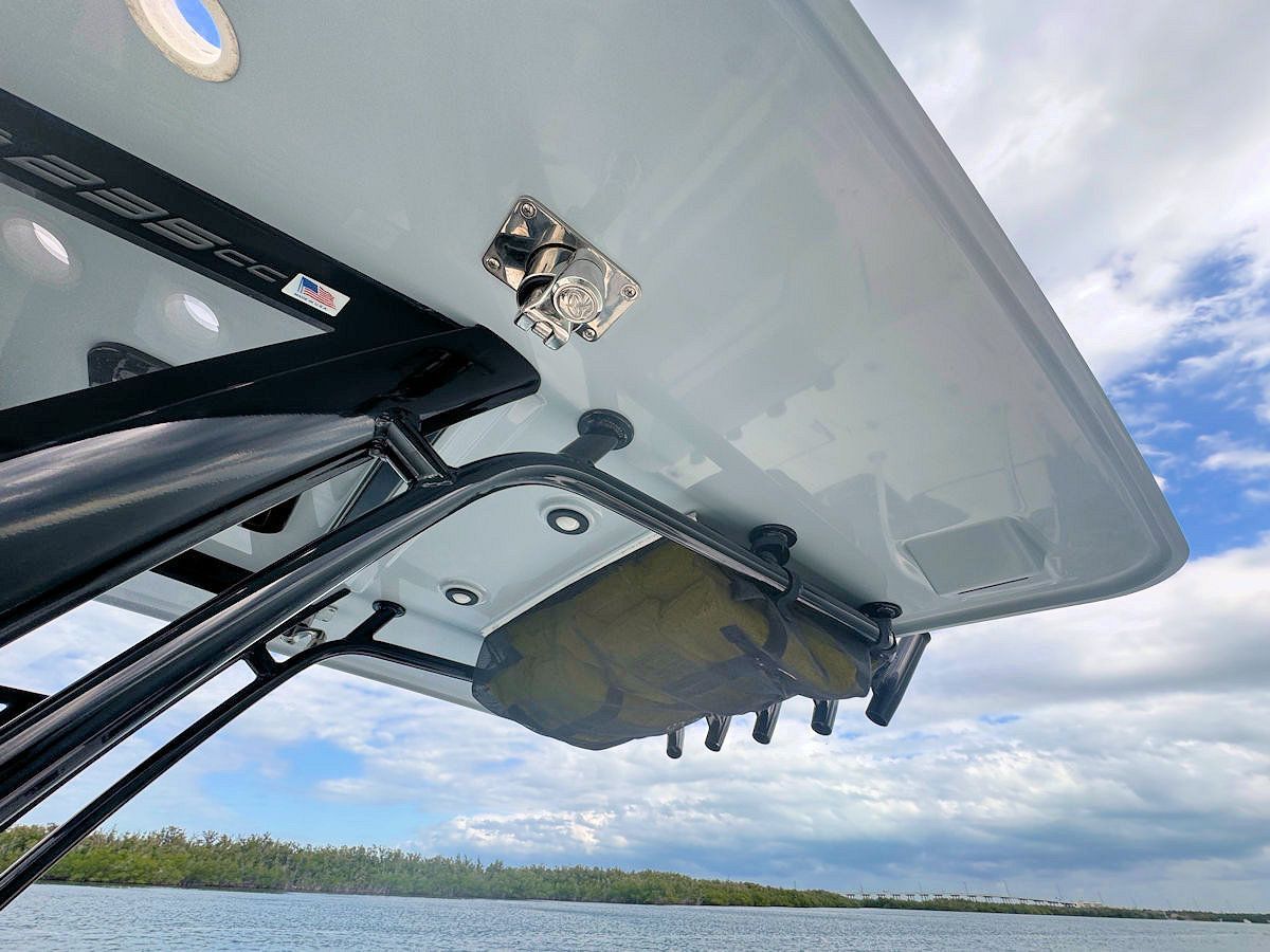 Boat's underside view, showing a gray top, black frame, fishing rod holders, and a bag over the water.