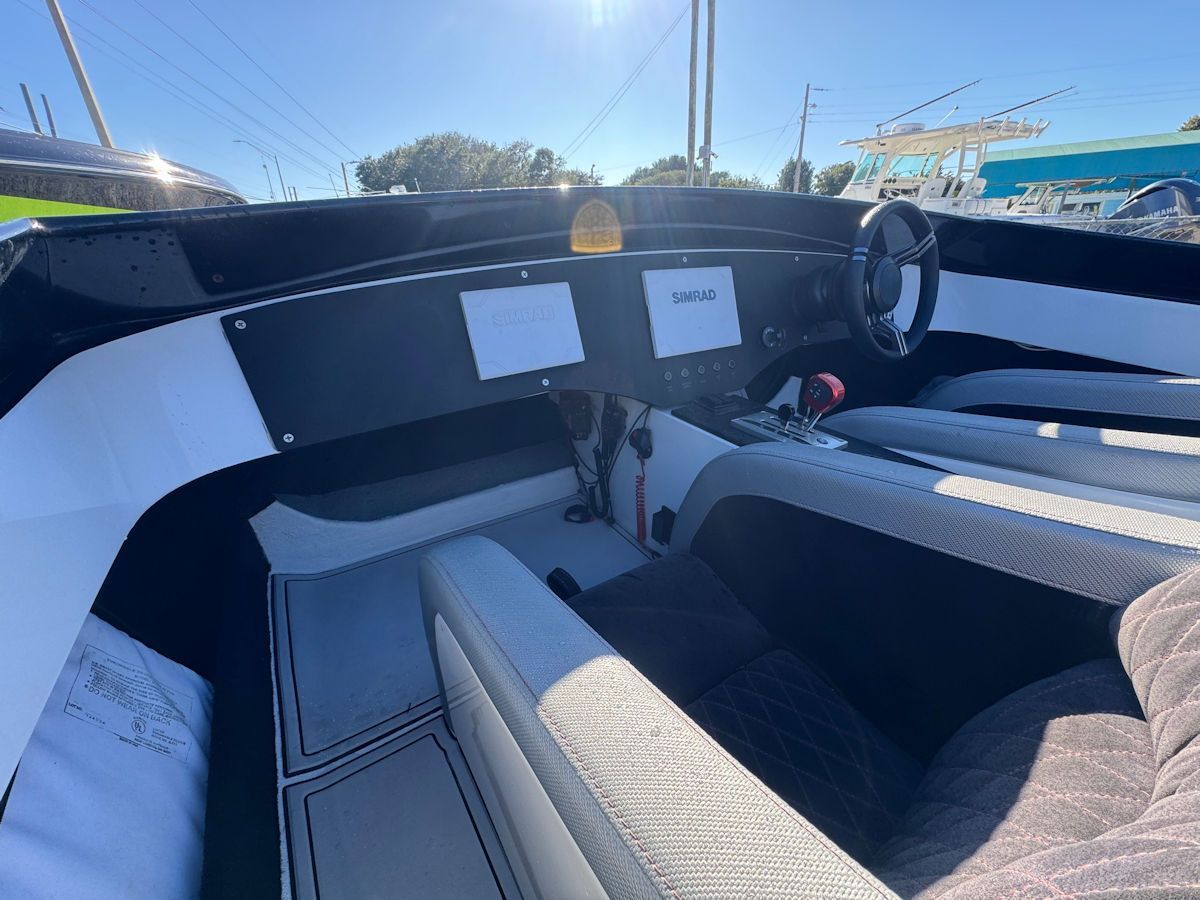 Interior view of a sleek, black and white speed boat cockpit with steering wheel and display screens.
