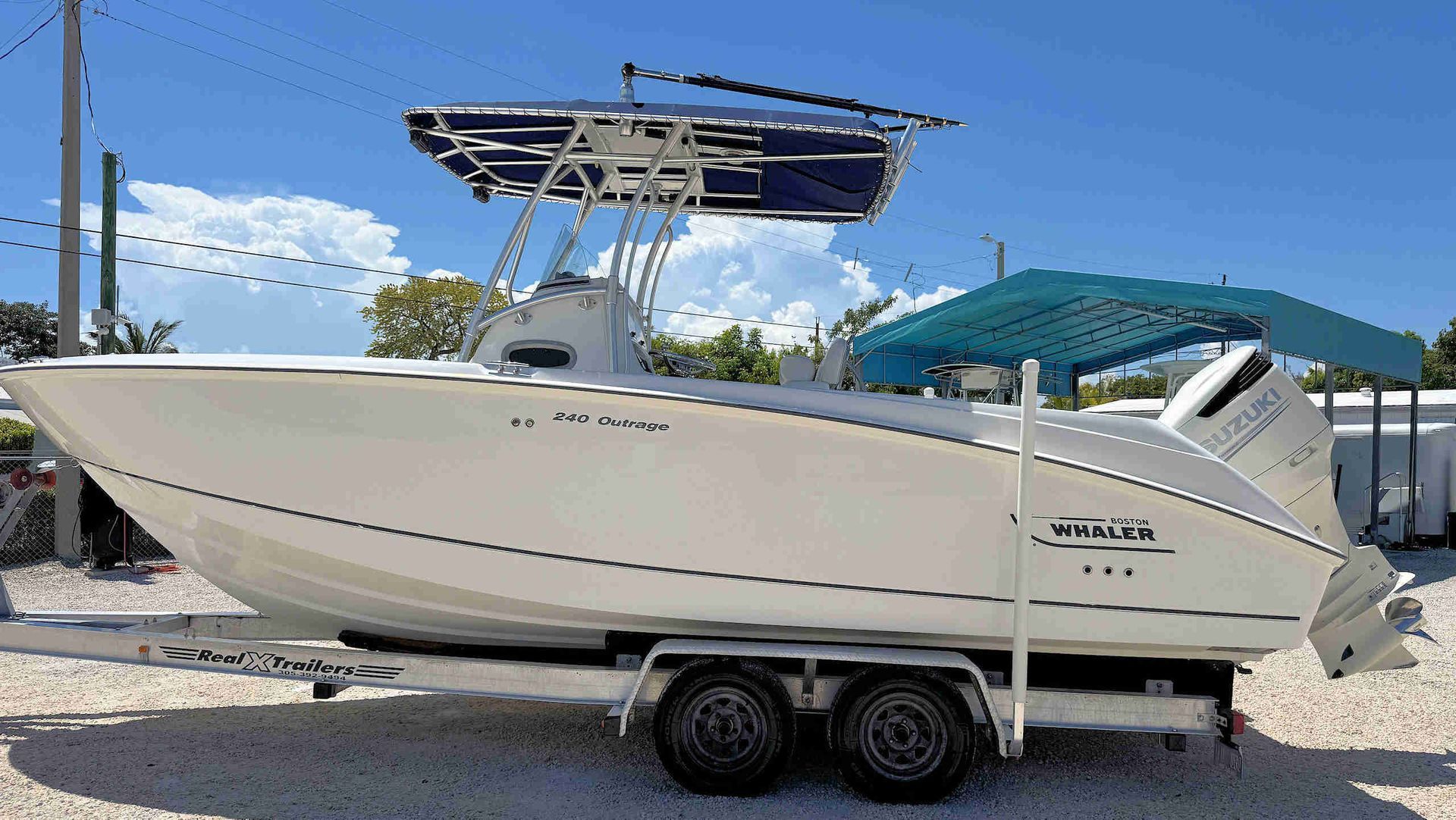 White center-console boat on a trailer, parked outdoors under a blue sky.