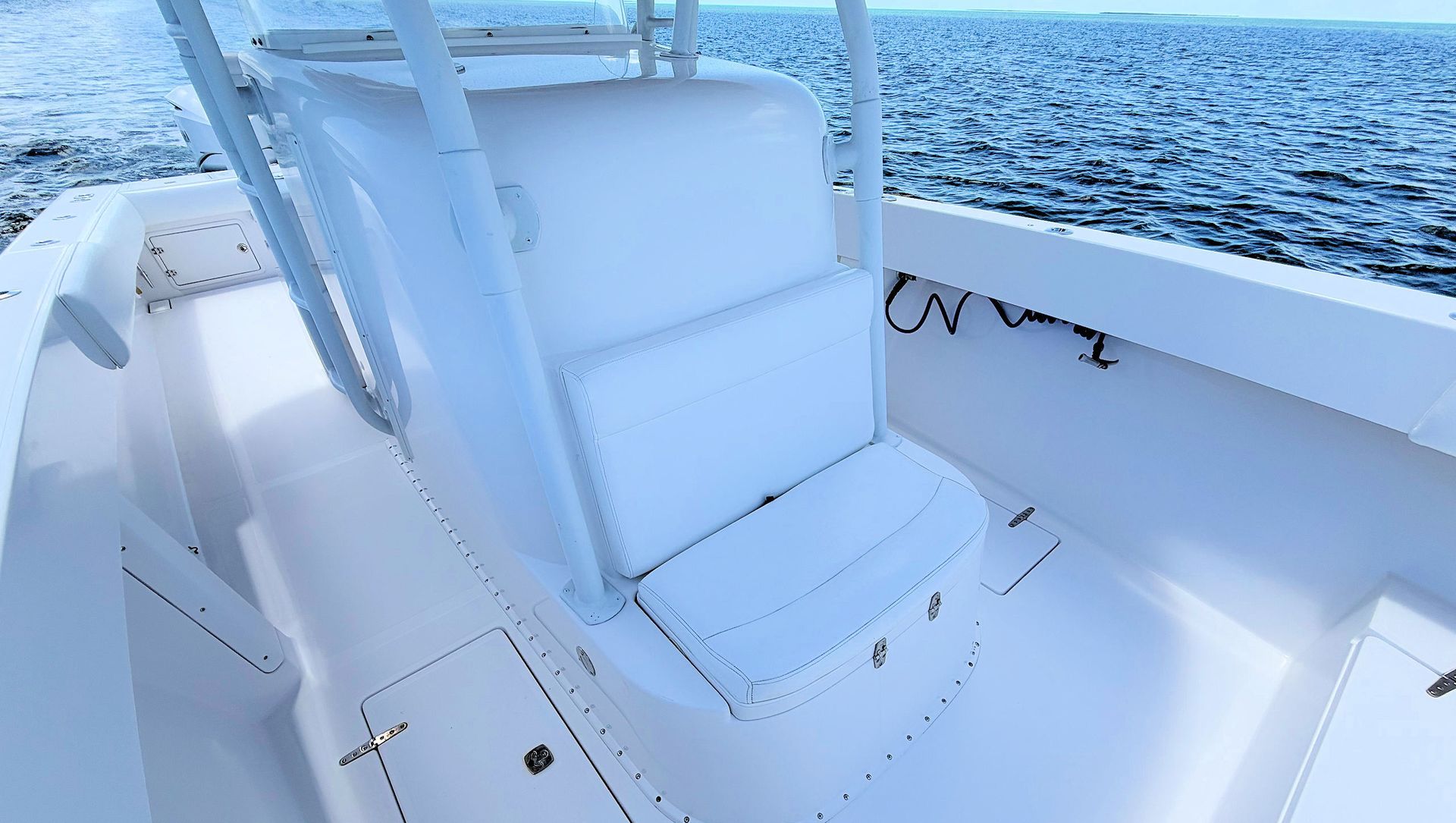 White cushioned boat seat on a yacht with blue ocean in the background