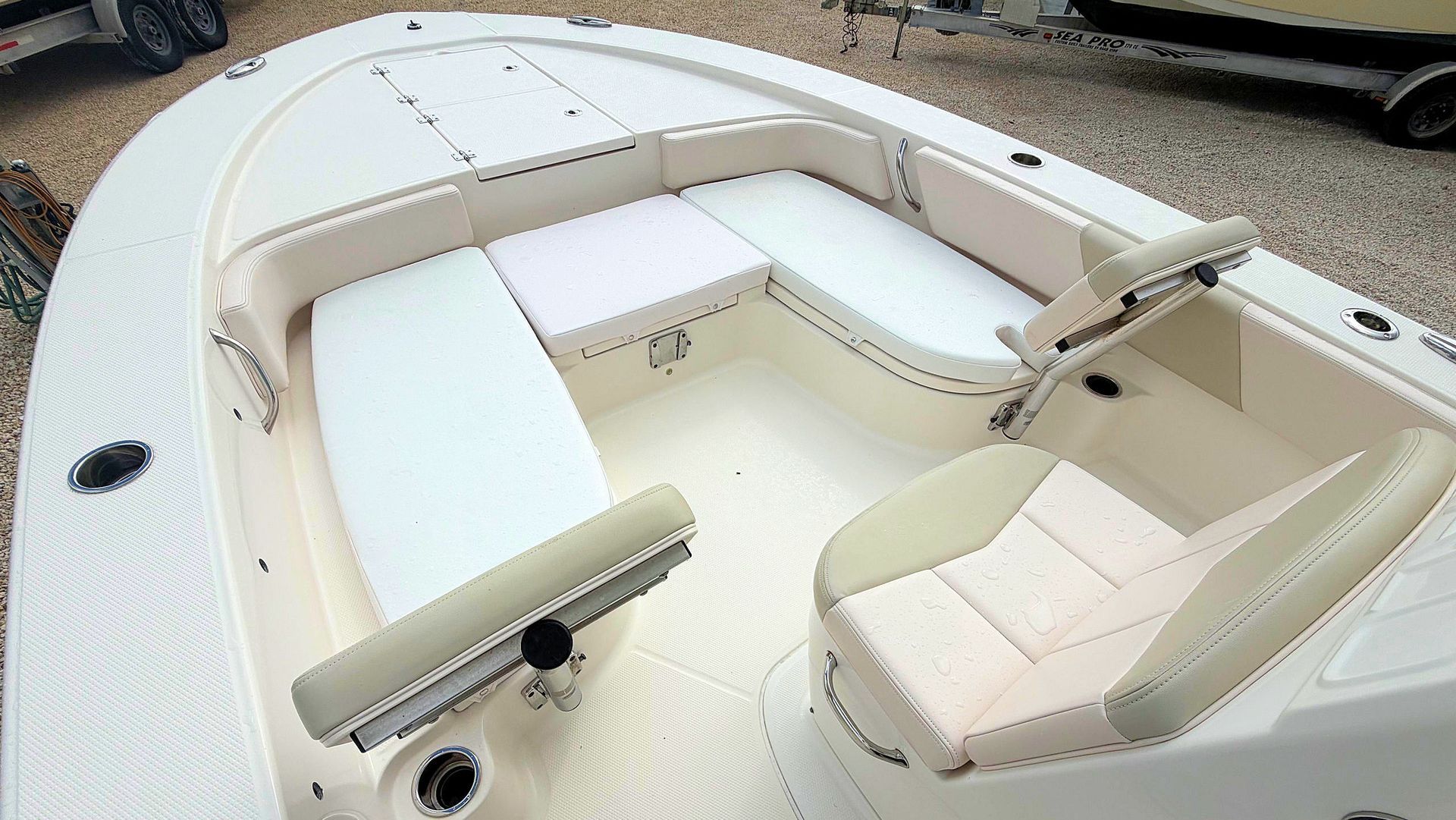 White boat interior with seating area with beige cushions and armrests on a deck