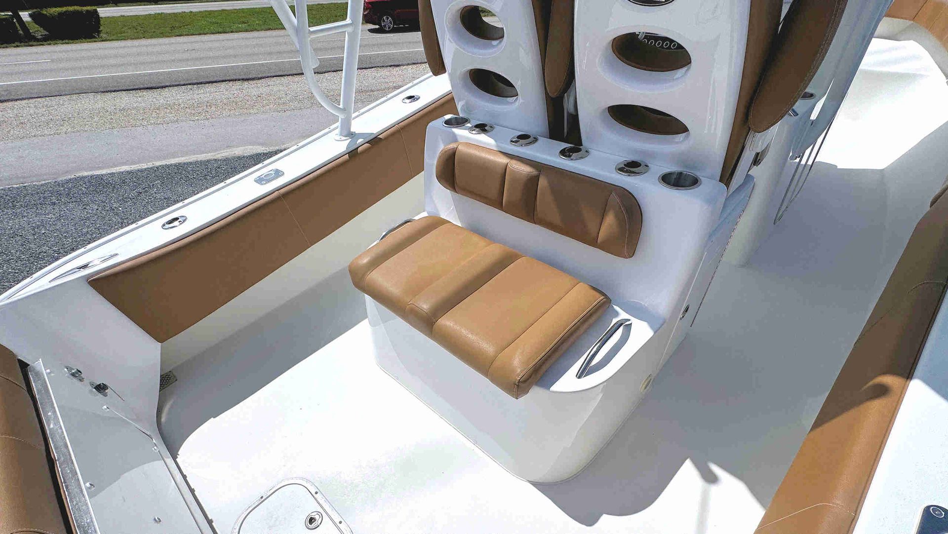 White boat cockpit with tan cushioned bench seats and a central backrest on a sunny day