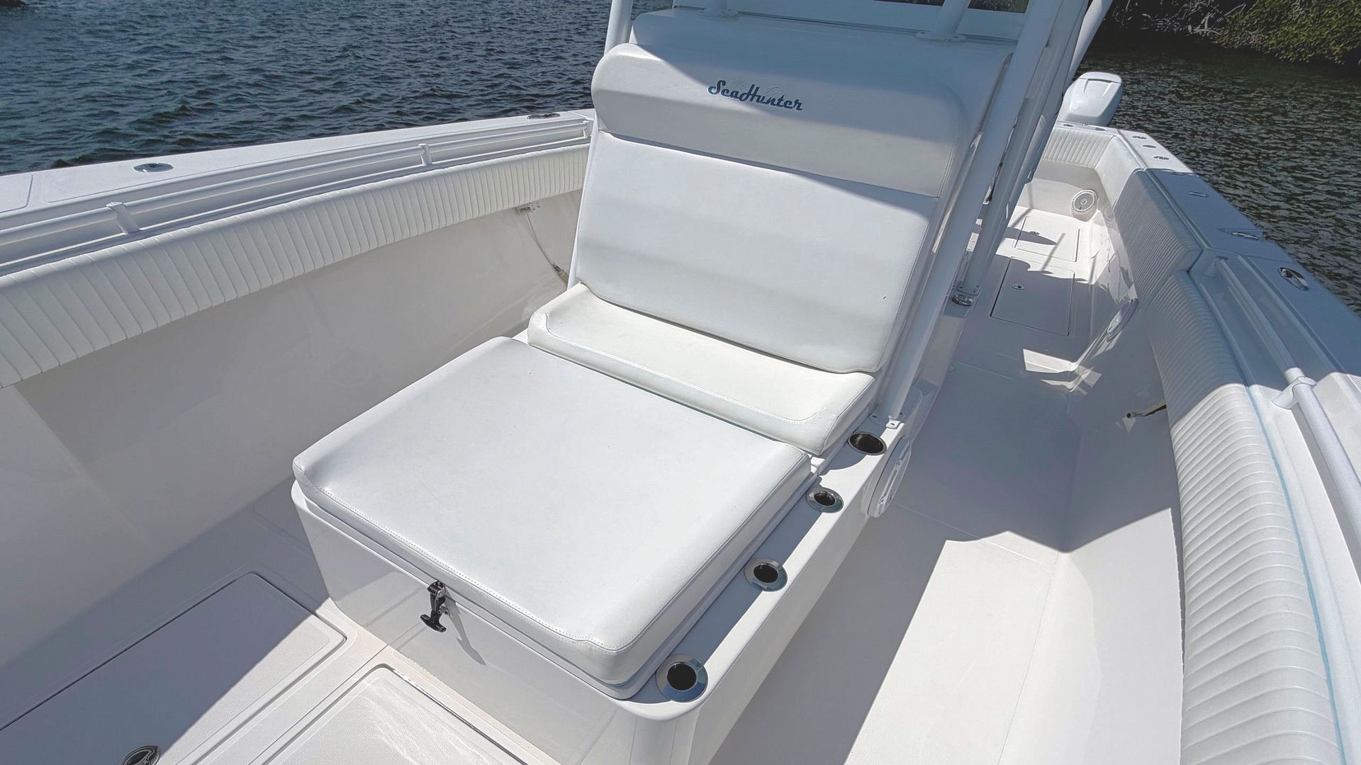 White cushioned boat seat on a small boat deck beside the water