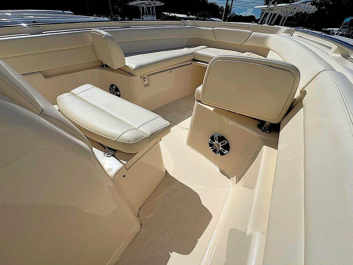 Boat interior with beige seating, speakers, and flooring.