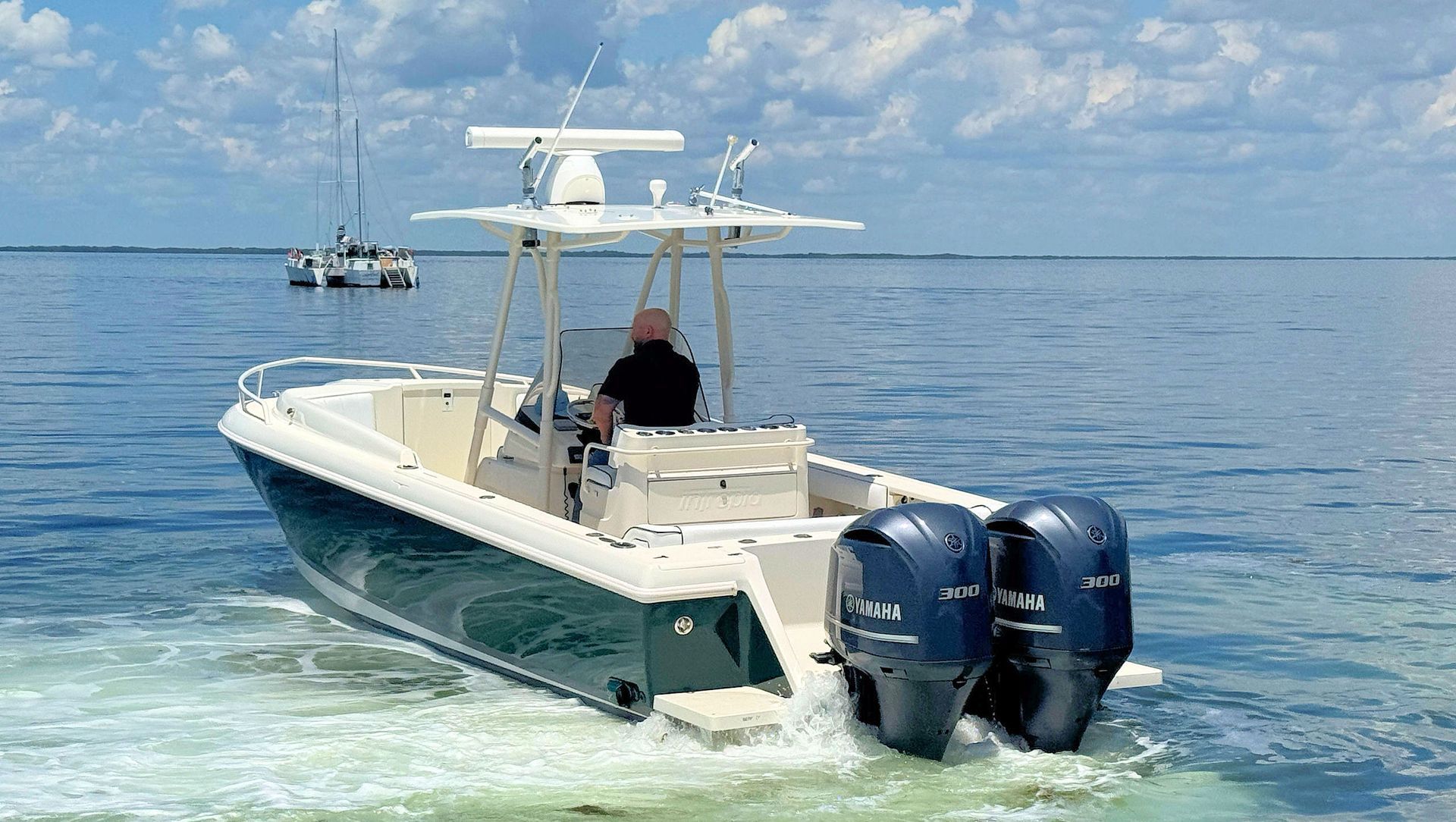 White and navy center console boat  on calm blue water under a partly cloudy sky.