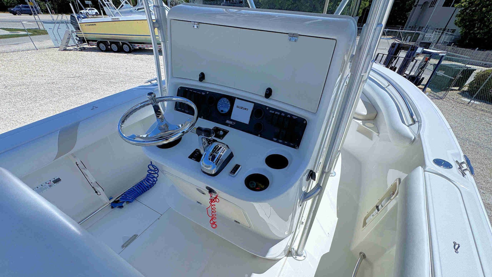 White boat helm with control panel, steering wheel, and cushioned helm seat on a sunny deck