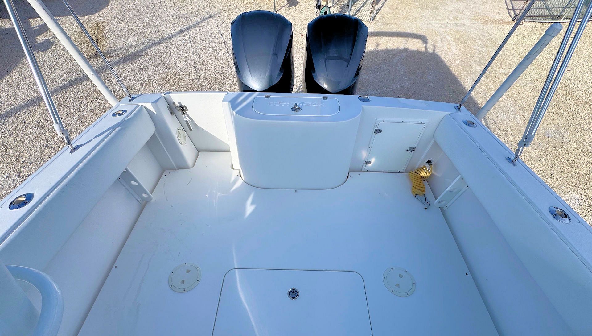 Empty white boat cockpit with two Yamaha engines and railings on a gravel lot