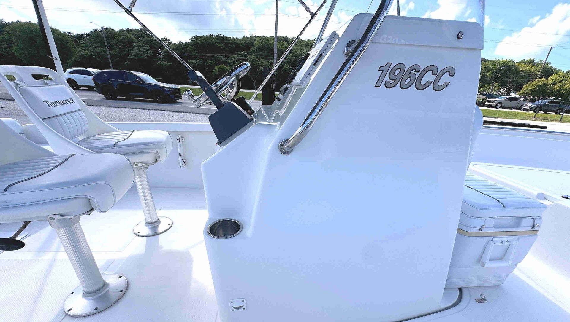 White Tidewater skiff center-console  with swivel captain's chairs under a bright sky.