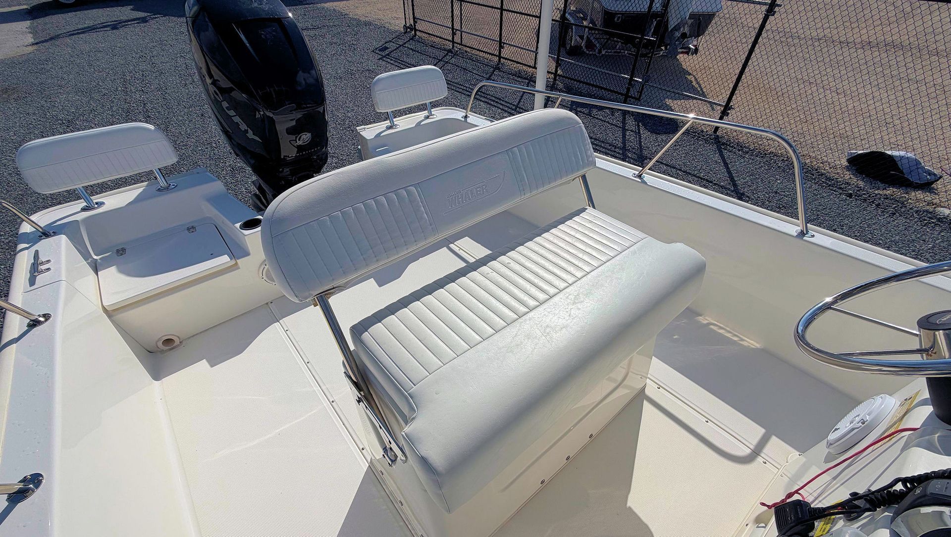 White boat seats and helm on a sunny deck with water visible beside the vessel