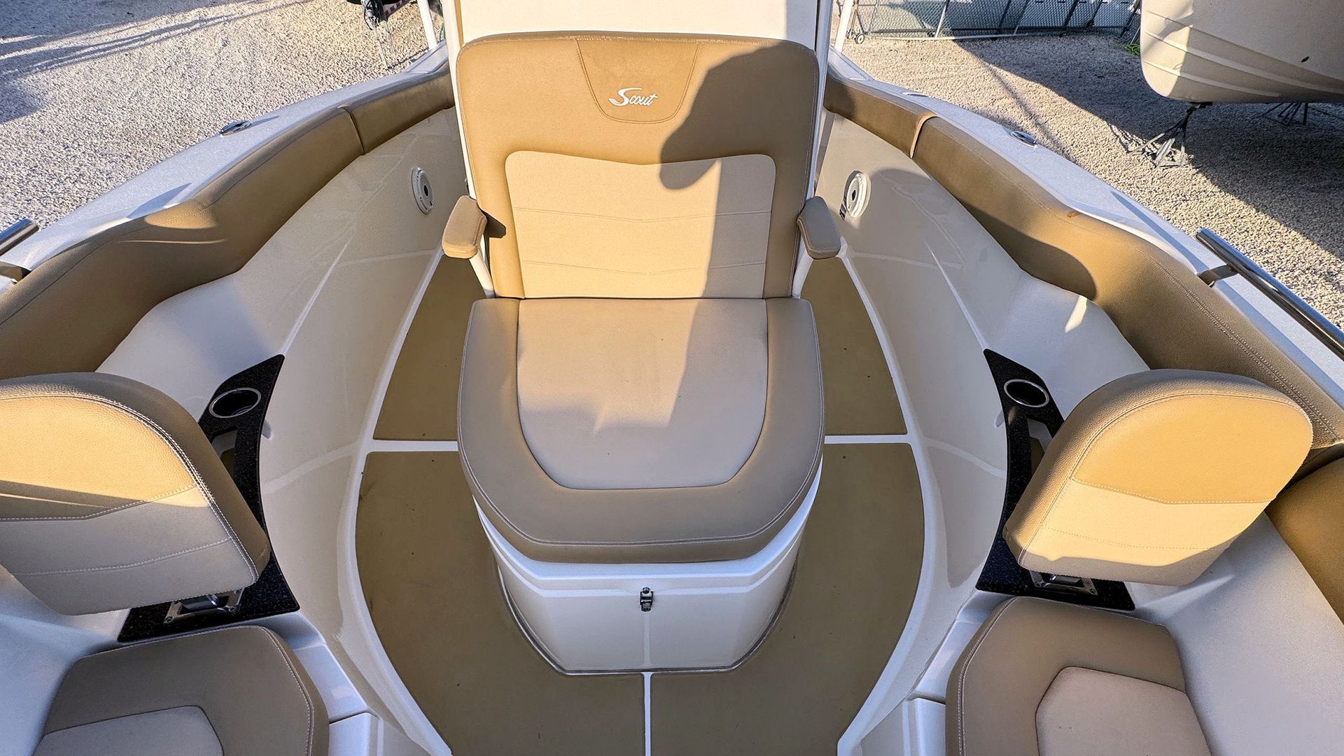 Boat bow looking towards the center console with tan and white seating and a central helm console, viewed from above