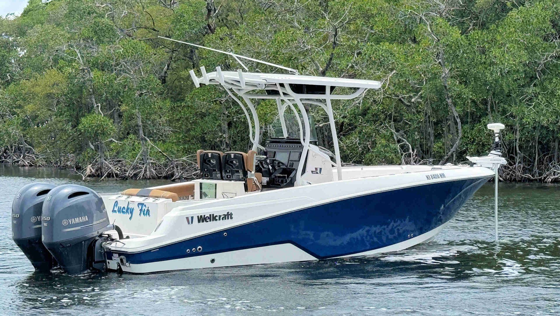 Wellcraft 242 Fisherman boat cruising on calm water near mangroves, with two outboard engines and a canopy