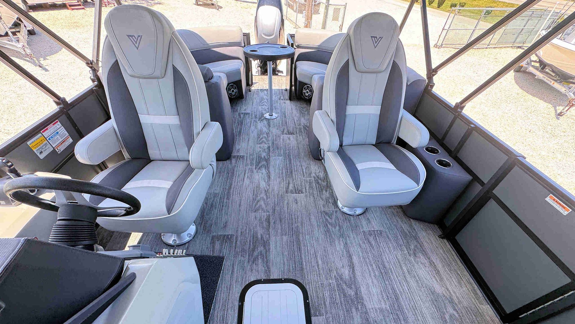Two gray reclining seats in a bright vehicle cabin with a carpeted floor and large windows.
