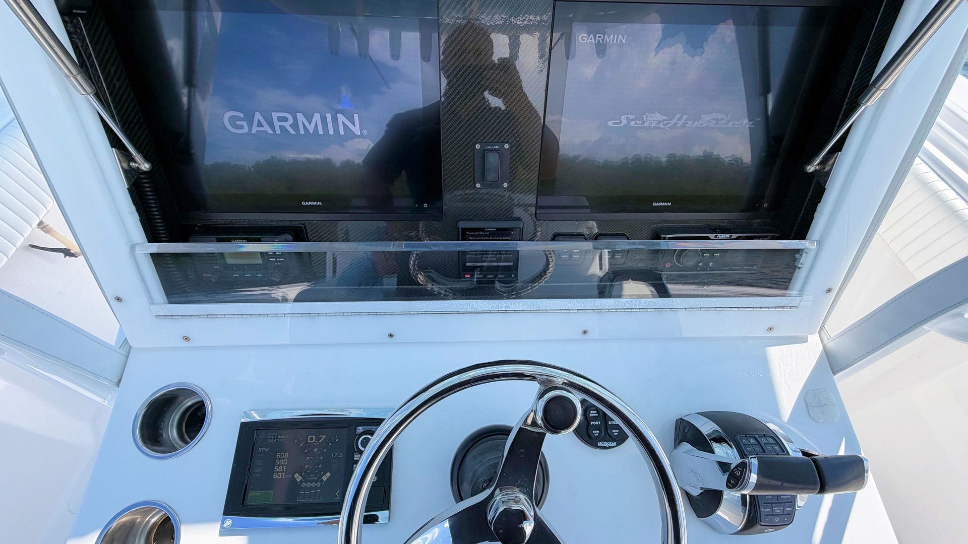 Boat helm with GPS display and steering wheel, viewed from the cockpit