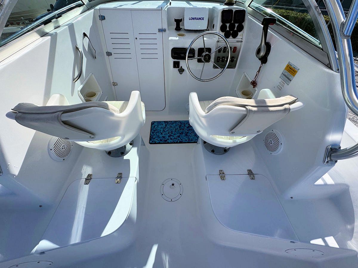 View inside a white boat's cockpit, with two seats and a dashboard.