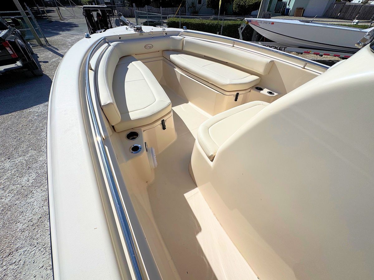 Interior of a beige motorboat with cushioned seating and cup holders.