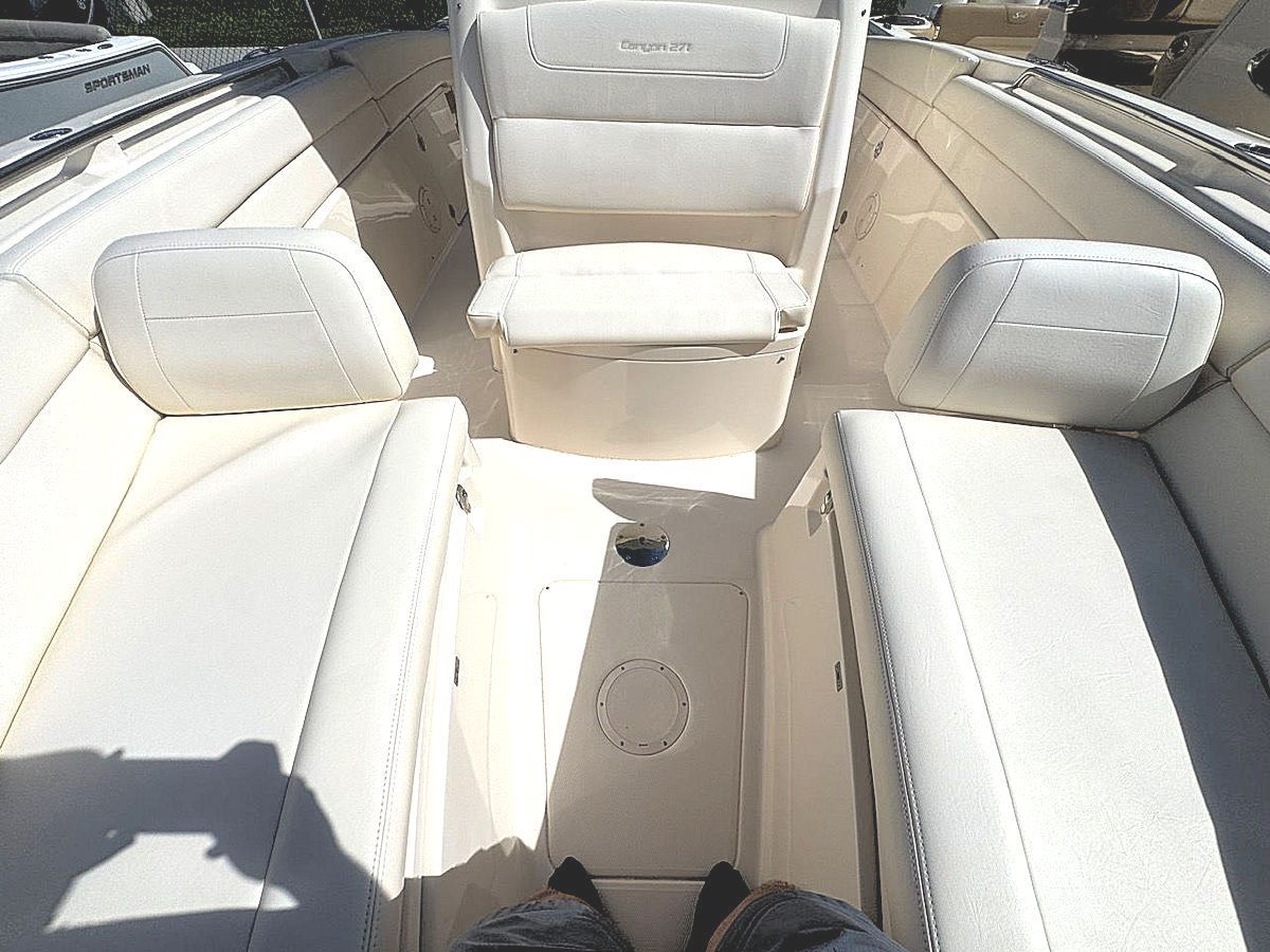 Interior of a boat with white seats. A person's legs and feet are visible in the center.