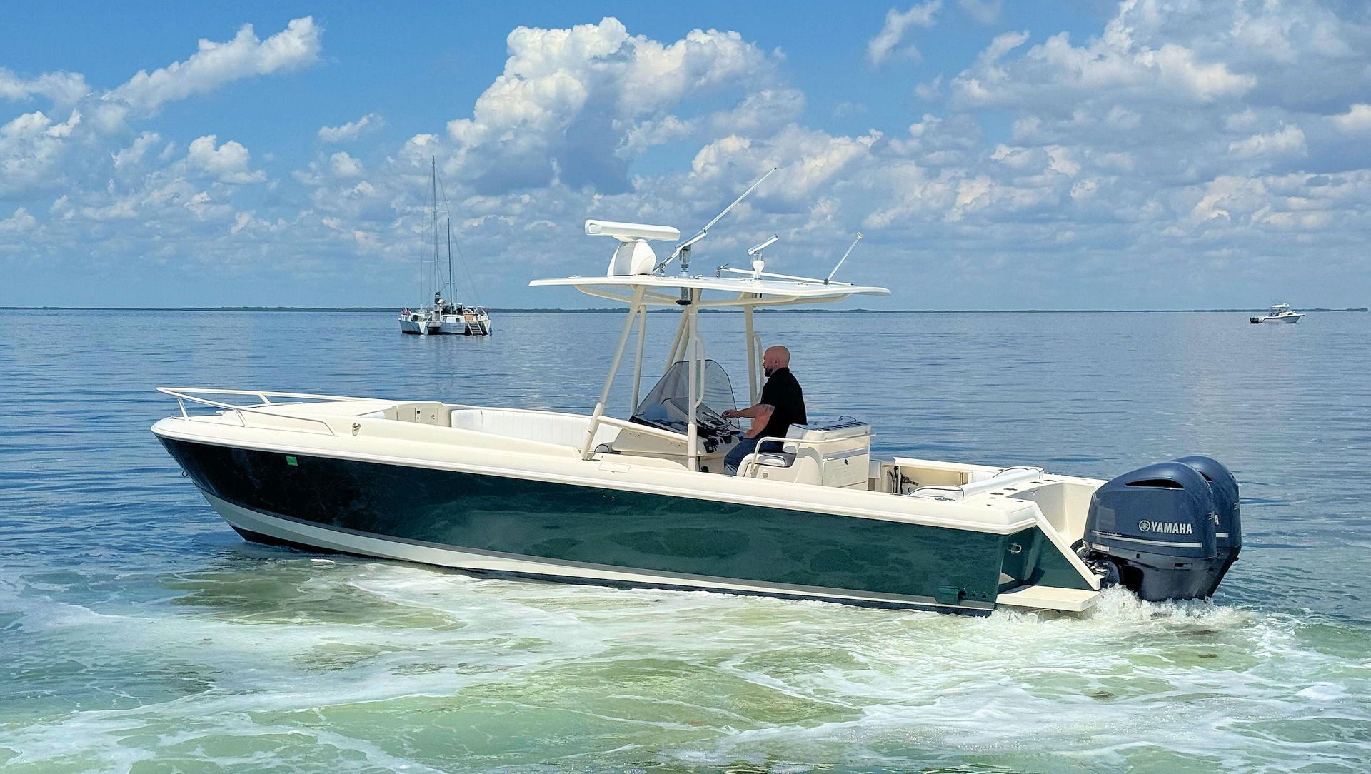 White and navy center console boat  on calm blue water under a partly cloudy sky.