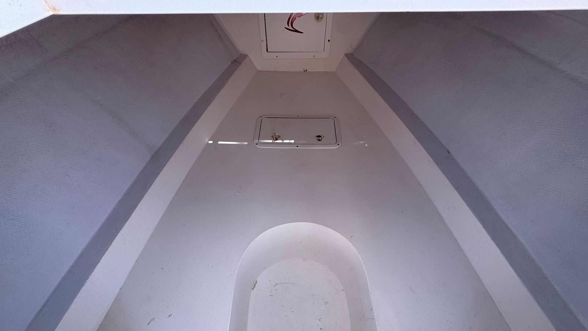 Interior view of a narrow white tunnel with two rectangular vents near the ceiling