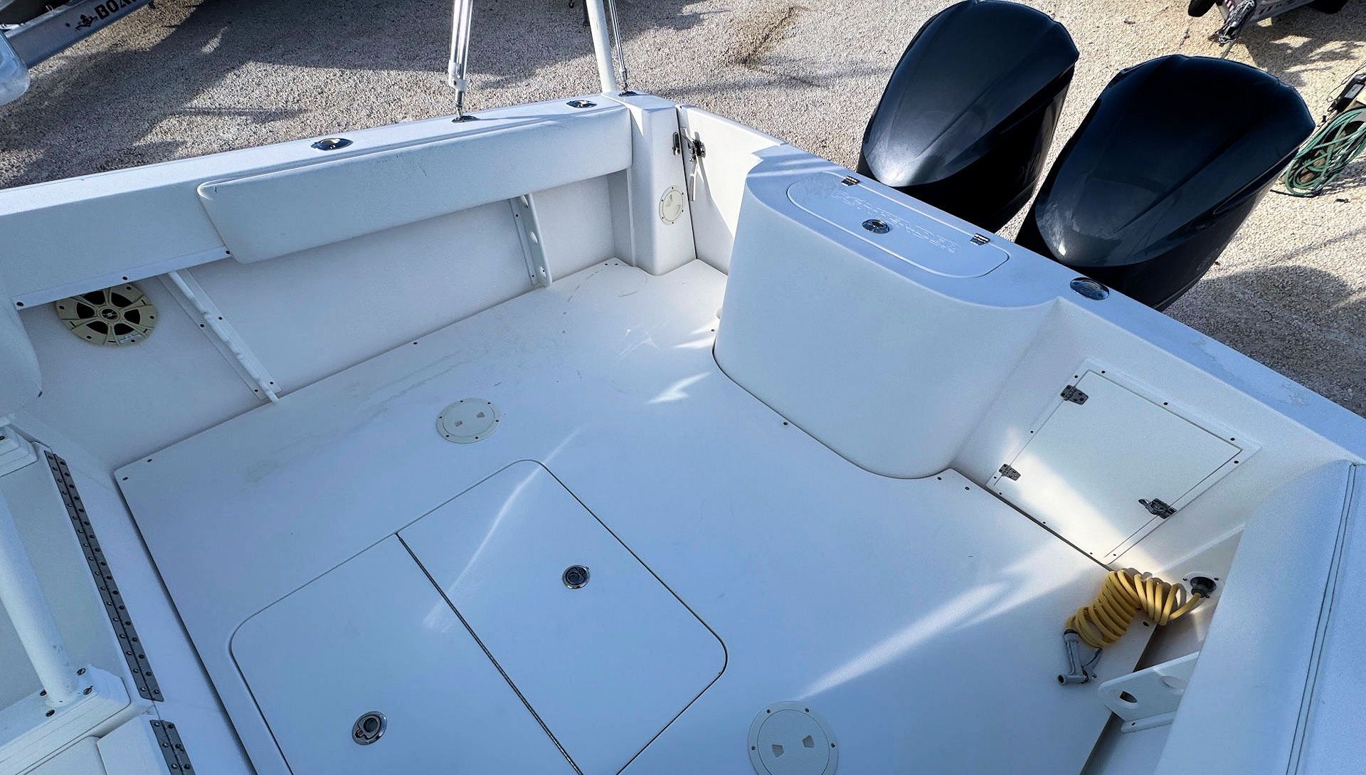 White boat deck with built-in seating and storage, viewed from above near the stern.