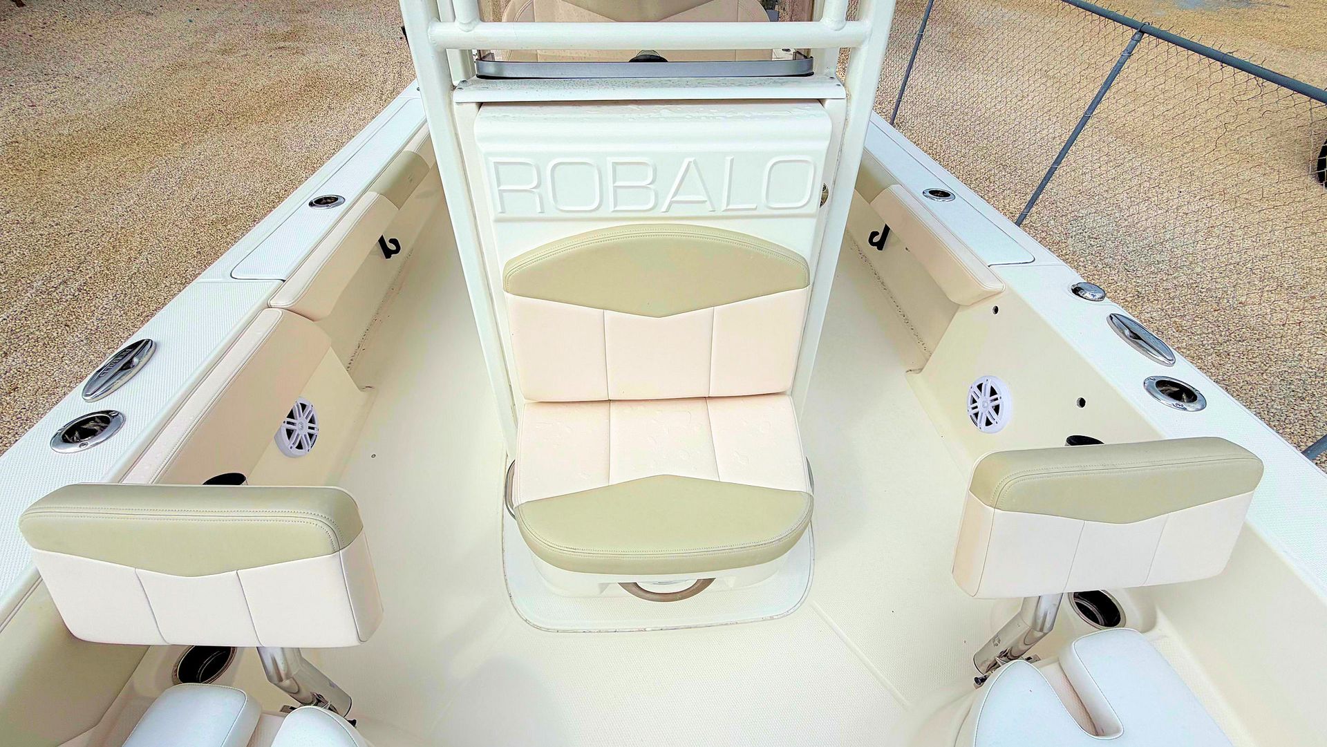 White boat interior with forward center console seat with beige cushioned seats and carpeted deck in bright sunlight