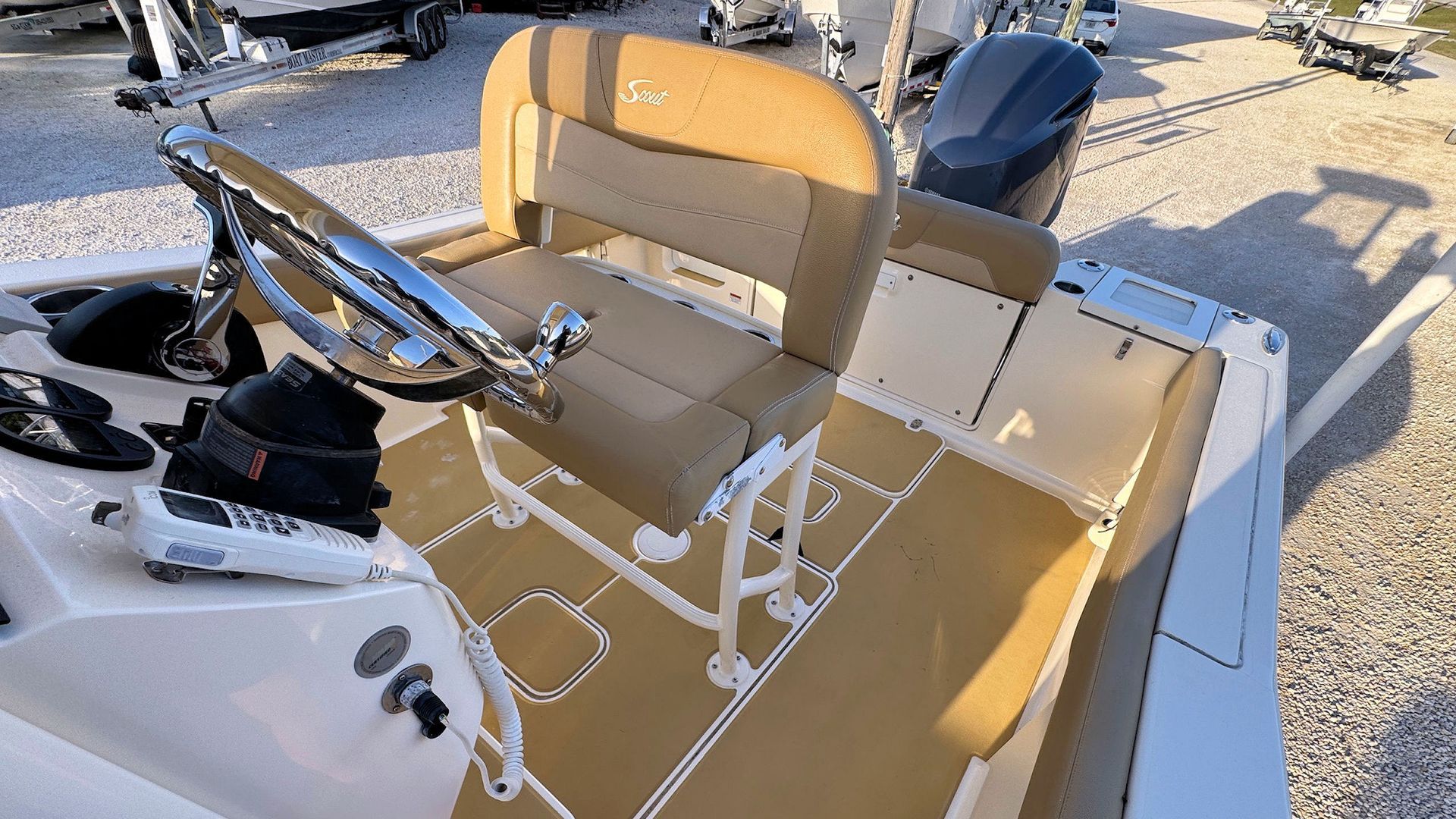 White center console deck with tan cushioned seating and an outboard engine in bright sunlight