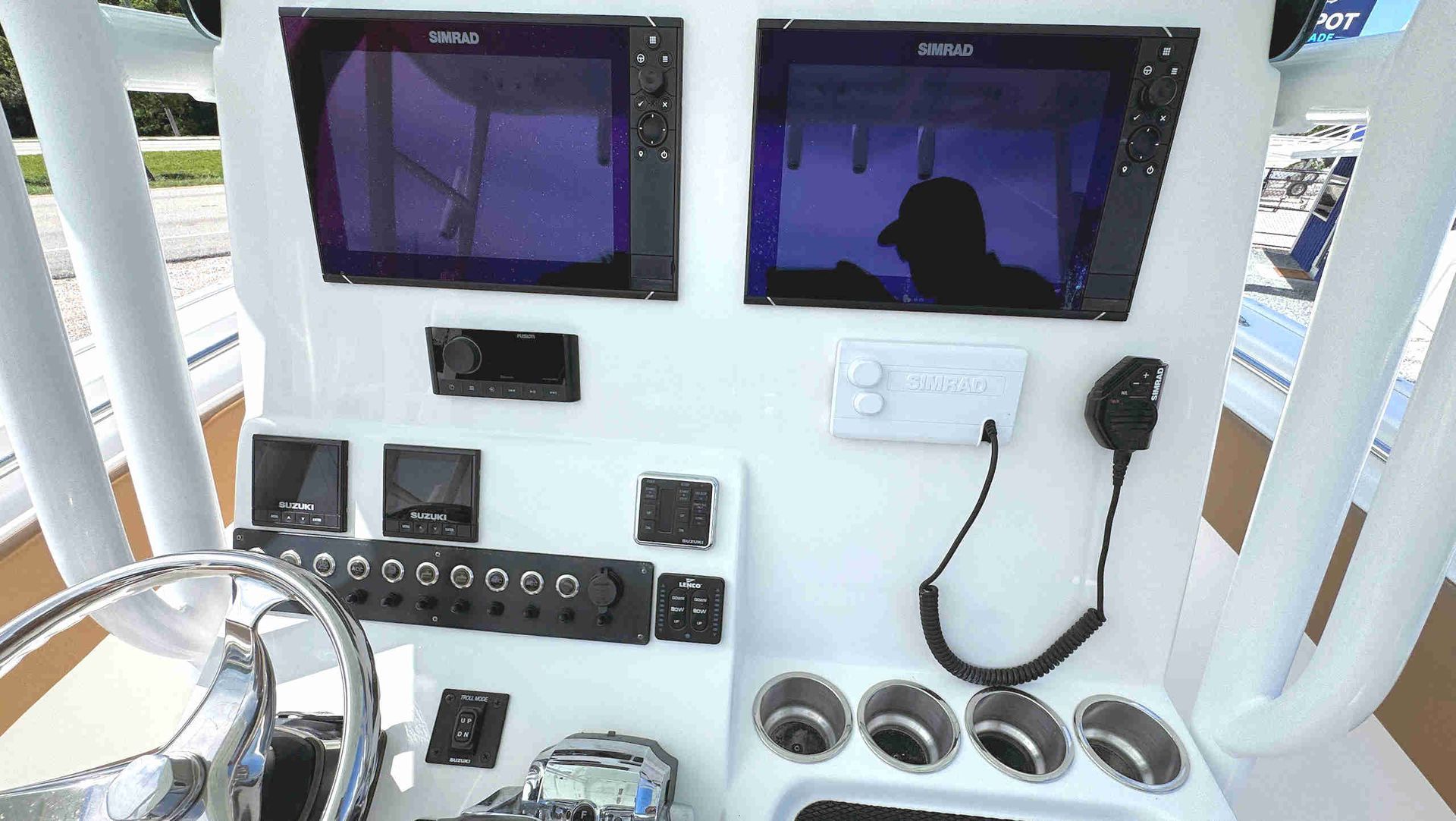 Boat helm with two marine displays, steering wheel, controls, and radio equipment