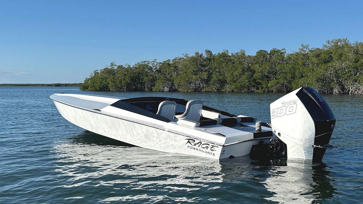 White speedboat with black accents on calm water, mangroves in background.