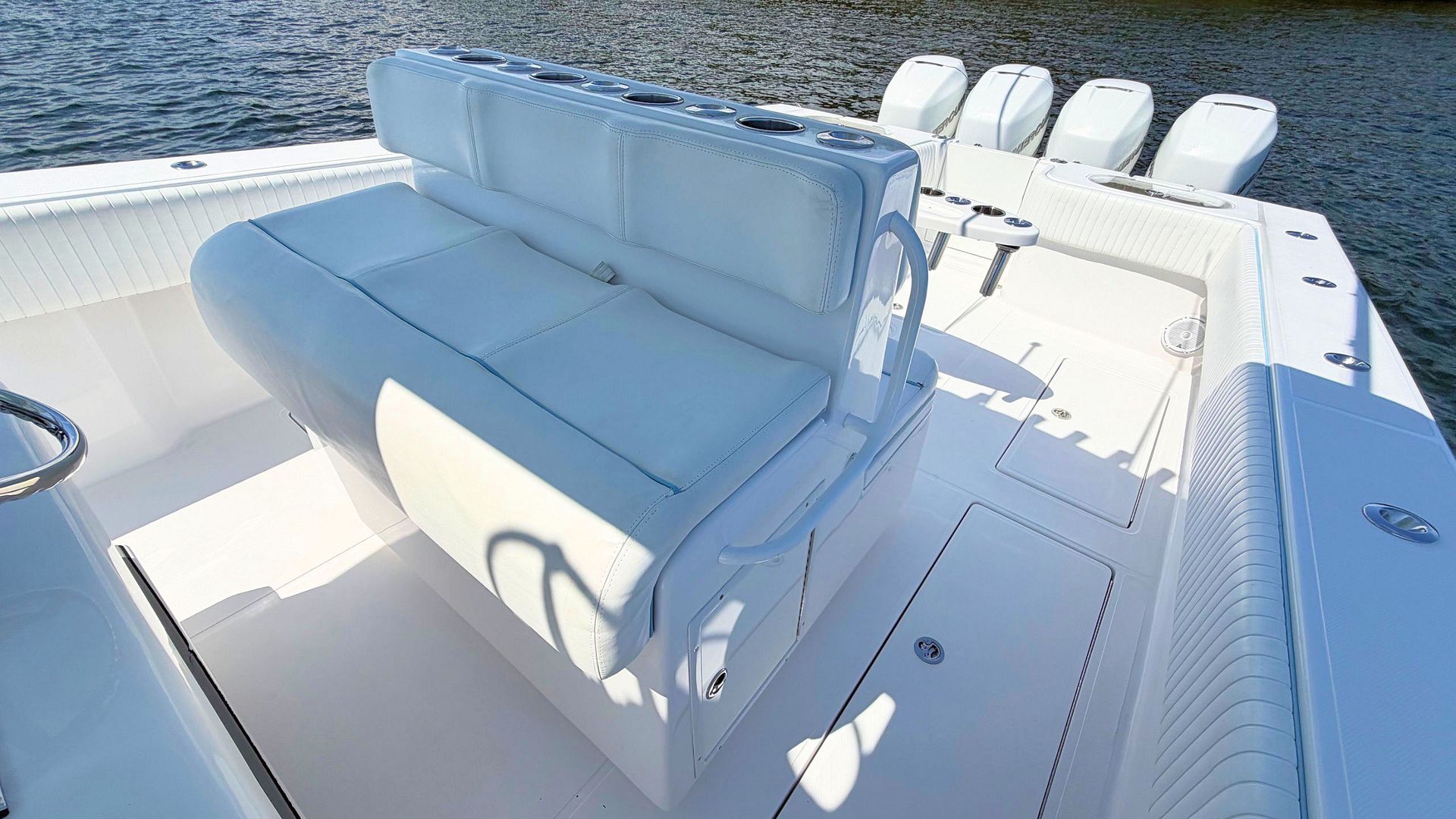 White cushioned bench seating on a boat deck with ocean water visible nearby