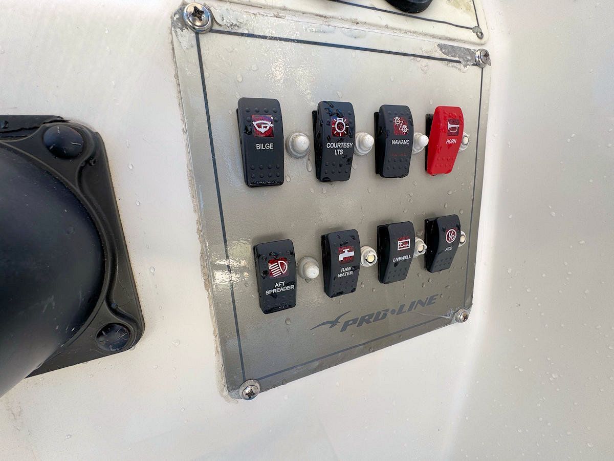 Control panel on a boat with eight black toggle switches and one red toggle switch.