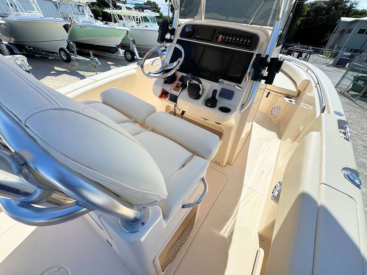 Interior of a boat with helm, seating, and controls. Beige and cream colors.