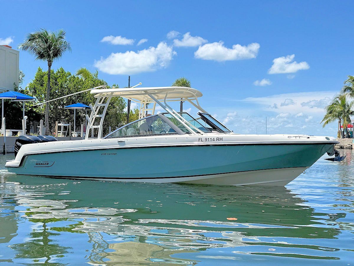 A blue and white motorboat on calm water with a turquoise hull and a sunny, blue sky backdrop.