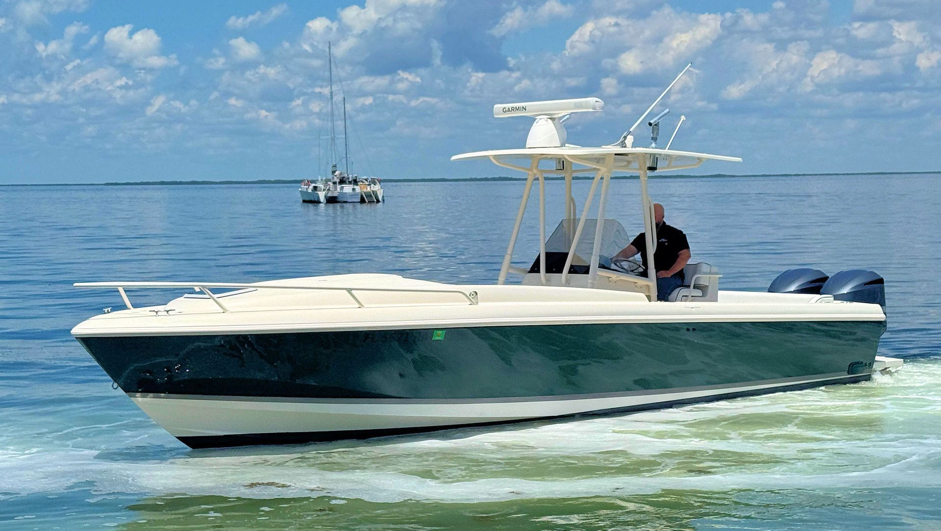 White and navy center console boat gliding across calm blue water under a clear sky
