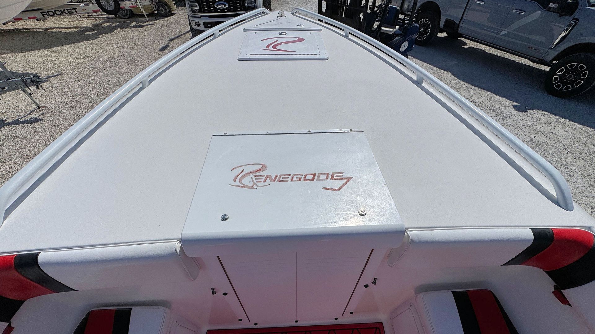 White racing boat deck with a hatch and red/black trim, seen from the stern at a dock.