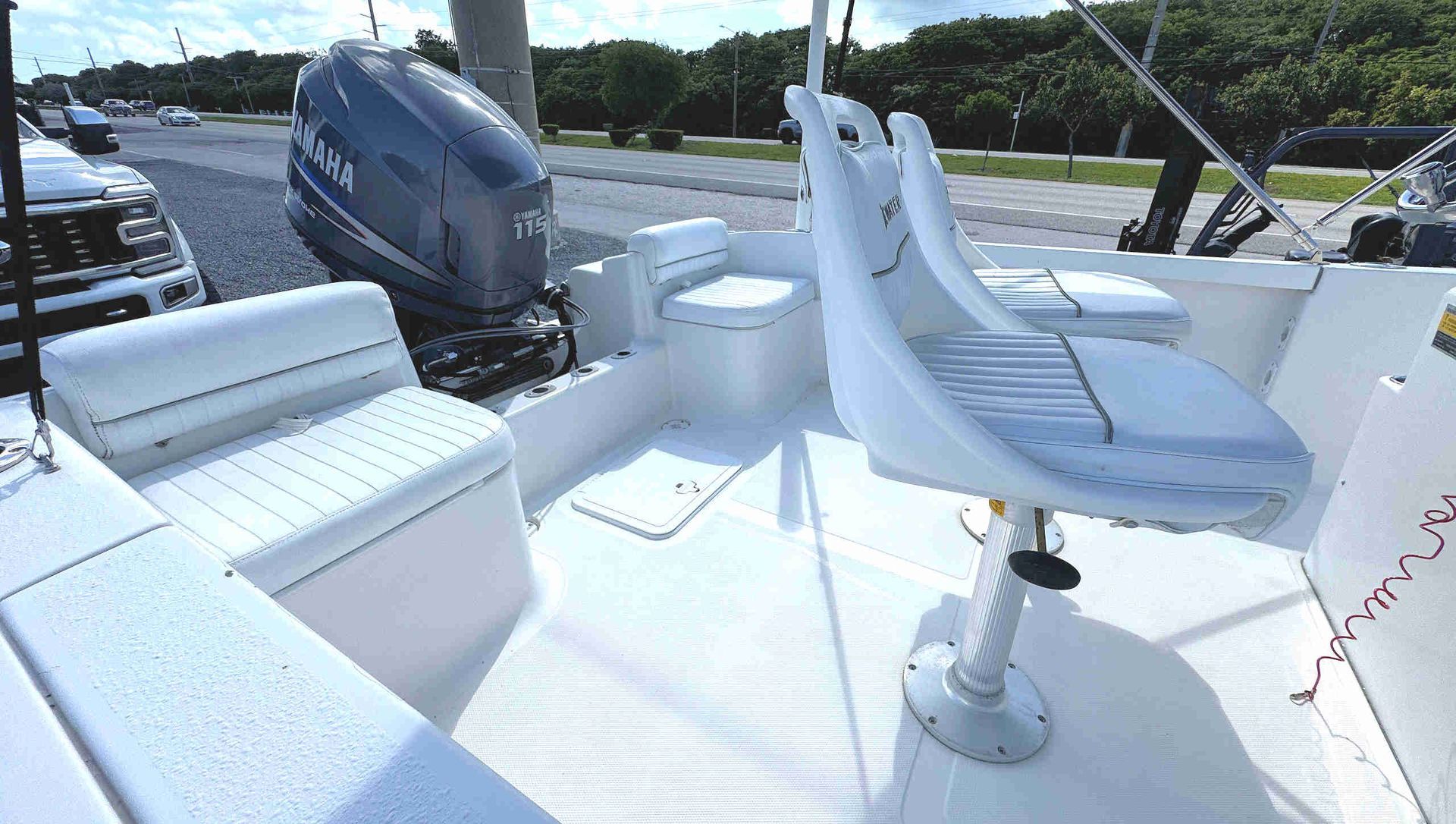 White boat cockpit with cushioned seats and a gray outboard motor on the stern deck.