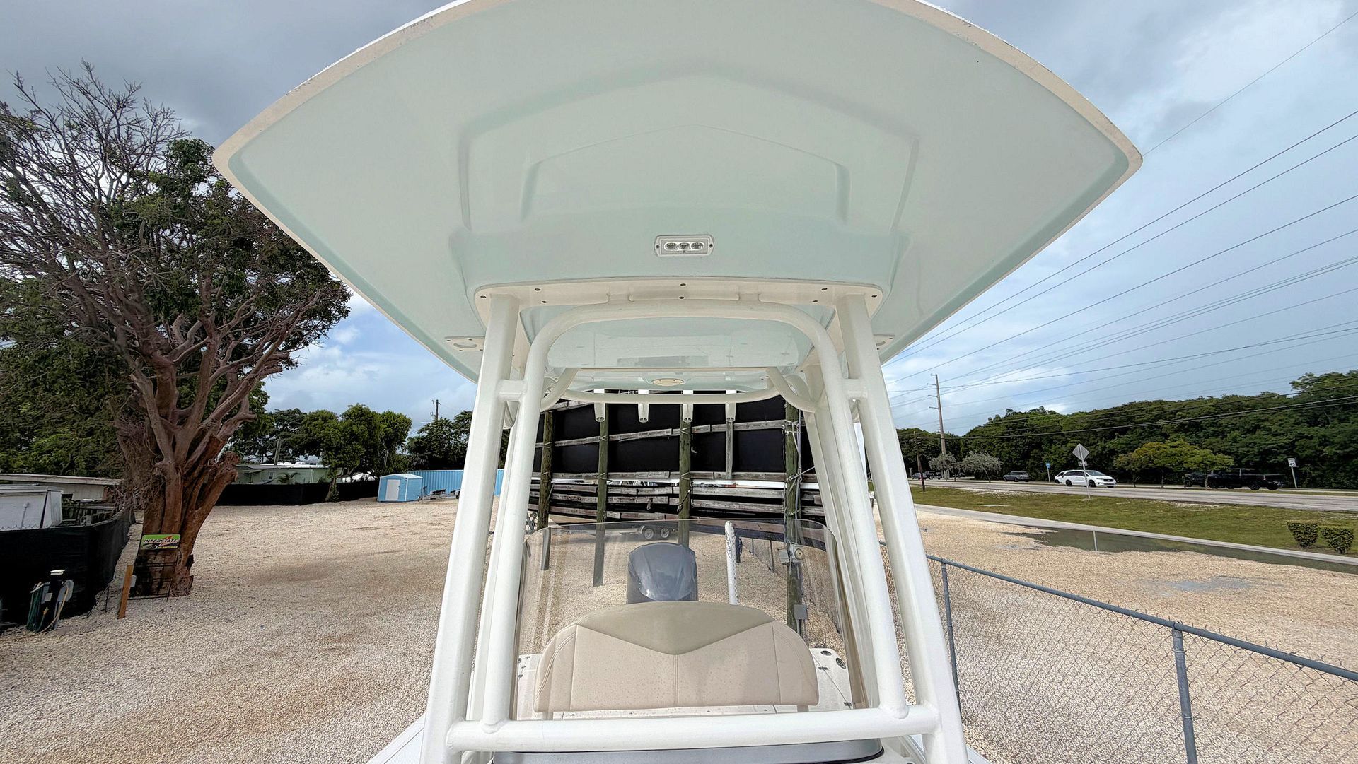 Front view of a hard t-top on a boat parked on a gravel lot under a cloudy sky
