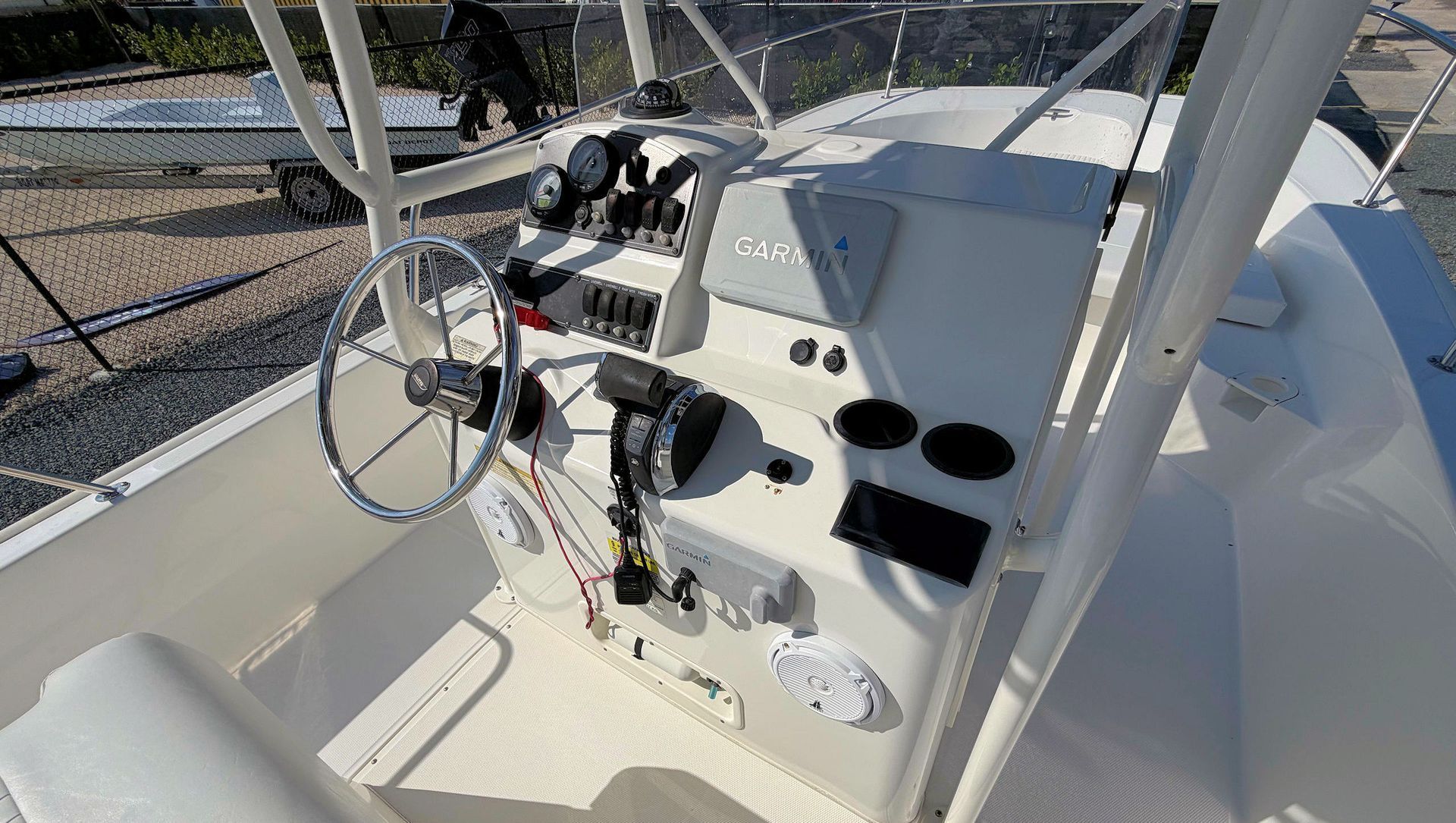 Boat helm with steering wheel, throttle controls, and cup holders in a marina cockpit